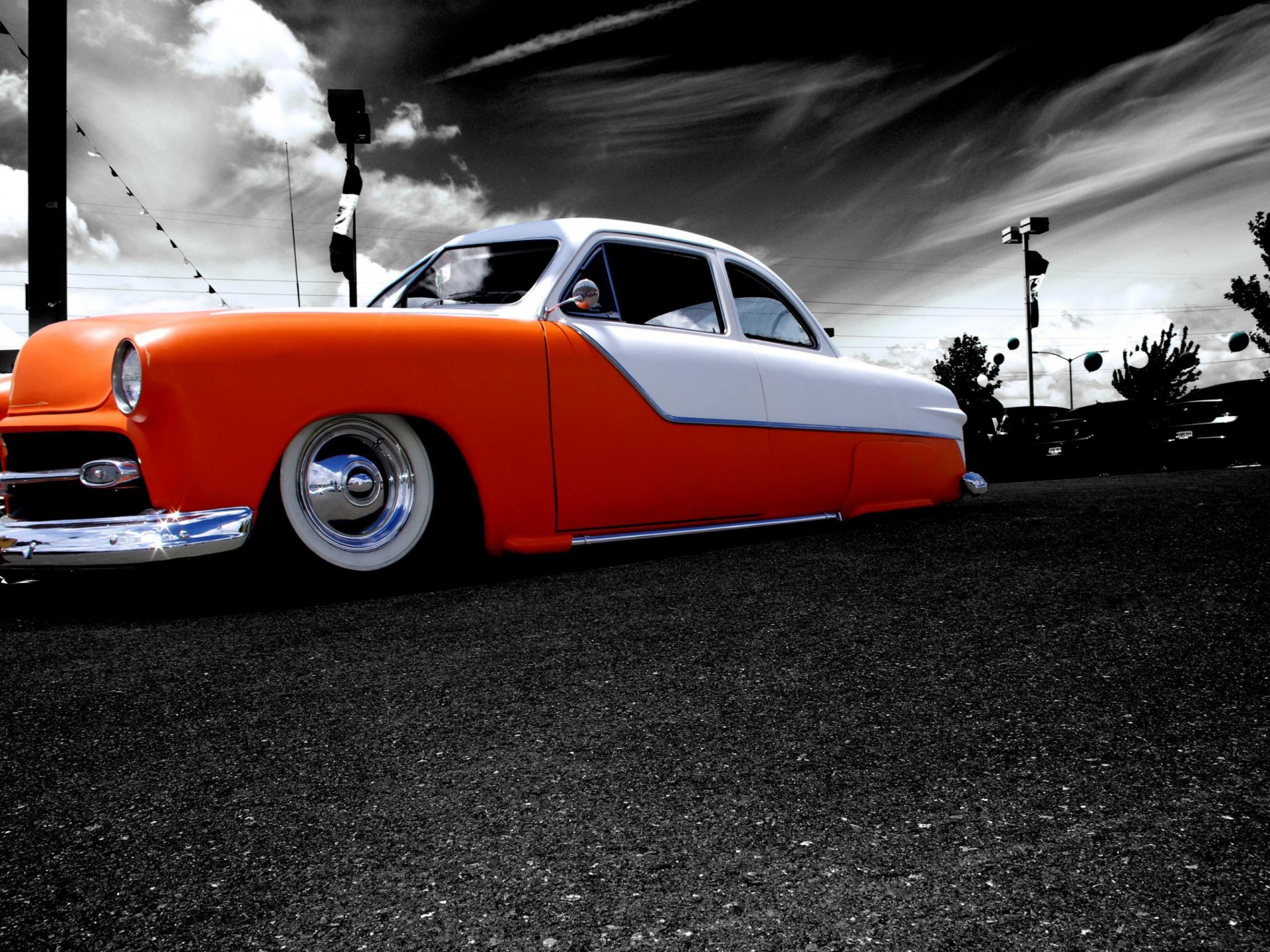 Low-angle shot of a lowered orange-and-white classic car under dramatic clouds — 2K Quad HD PC desktop wallpaper/background.