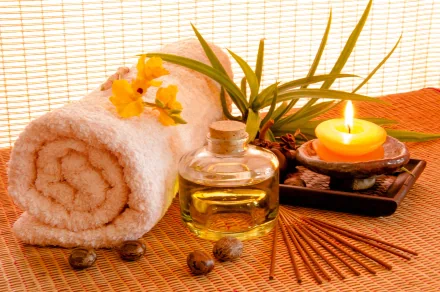 A serene spa scene featuring a rolled towel, essential oil, a lit candle, and decorative elements, creating a calming atmosphere. This 4K Ultra HD image serves as an inviting desktop wallpaper.