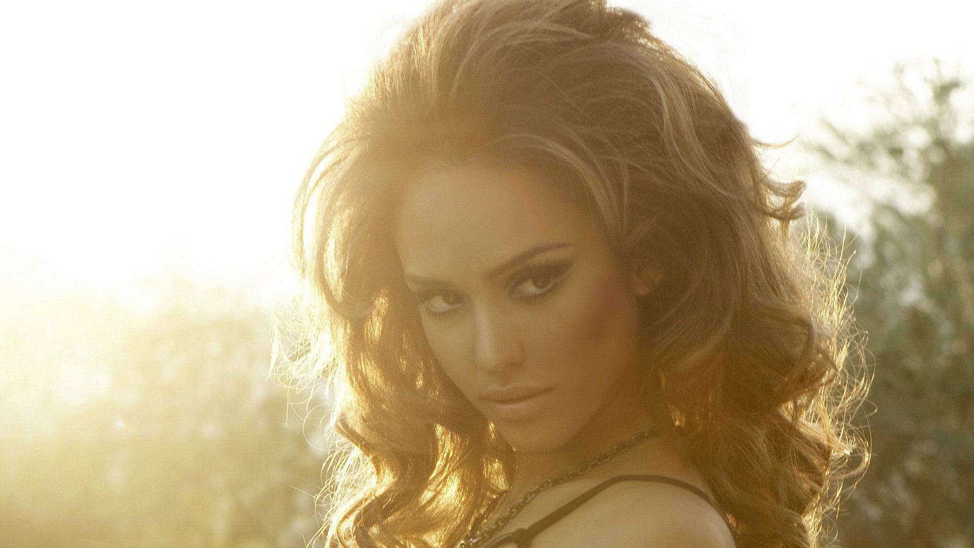 HD desktop wallpaper of celebrity Jessica Alba with soft golden sunlight highlighting her face and hair in an outdoor setting.