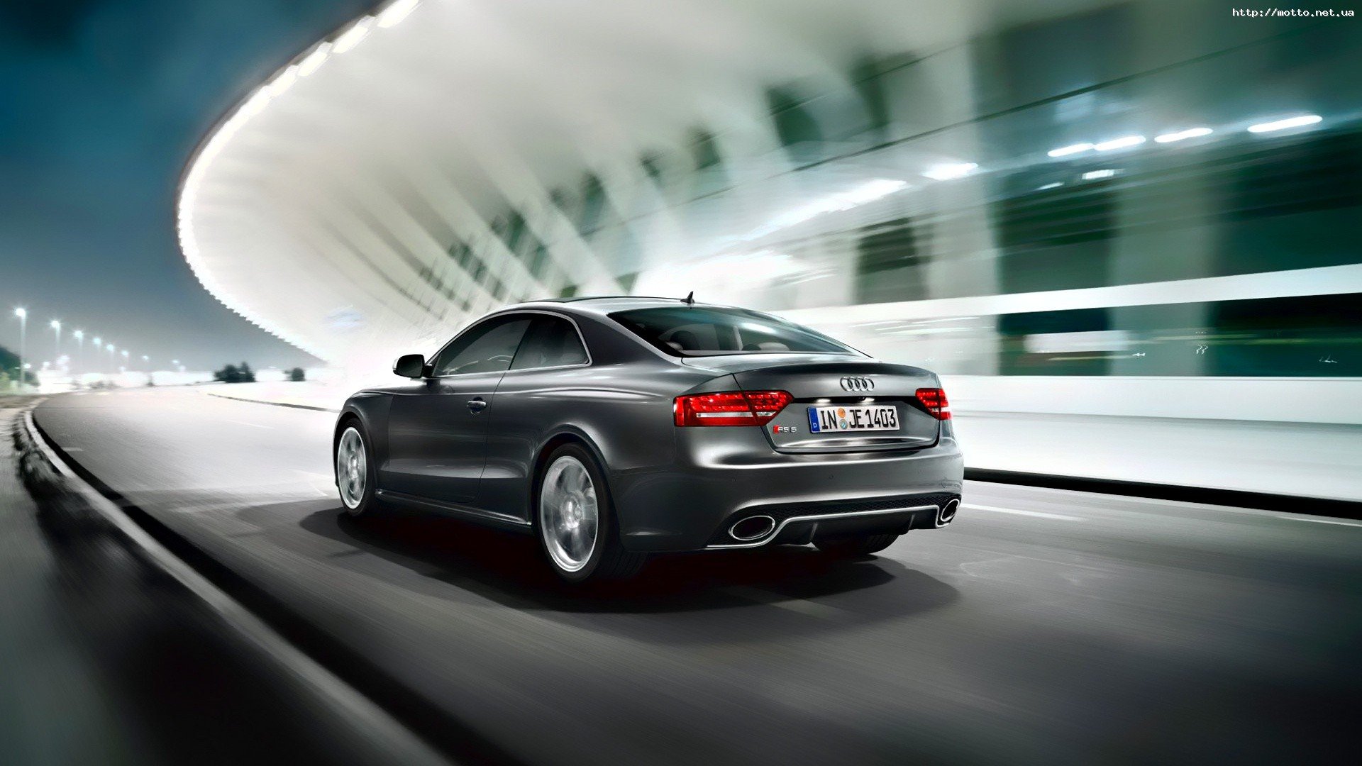 HD PC desktop wallpaper: sleek gray Audi RS5 coupe speeding past a futuristic illuminated building at night.