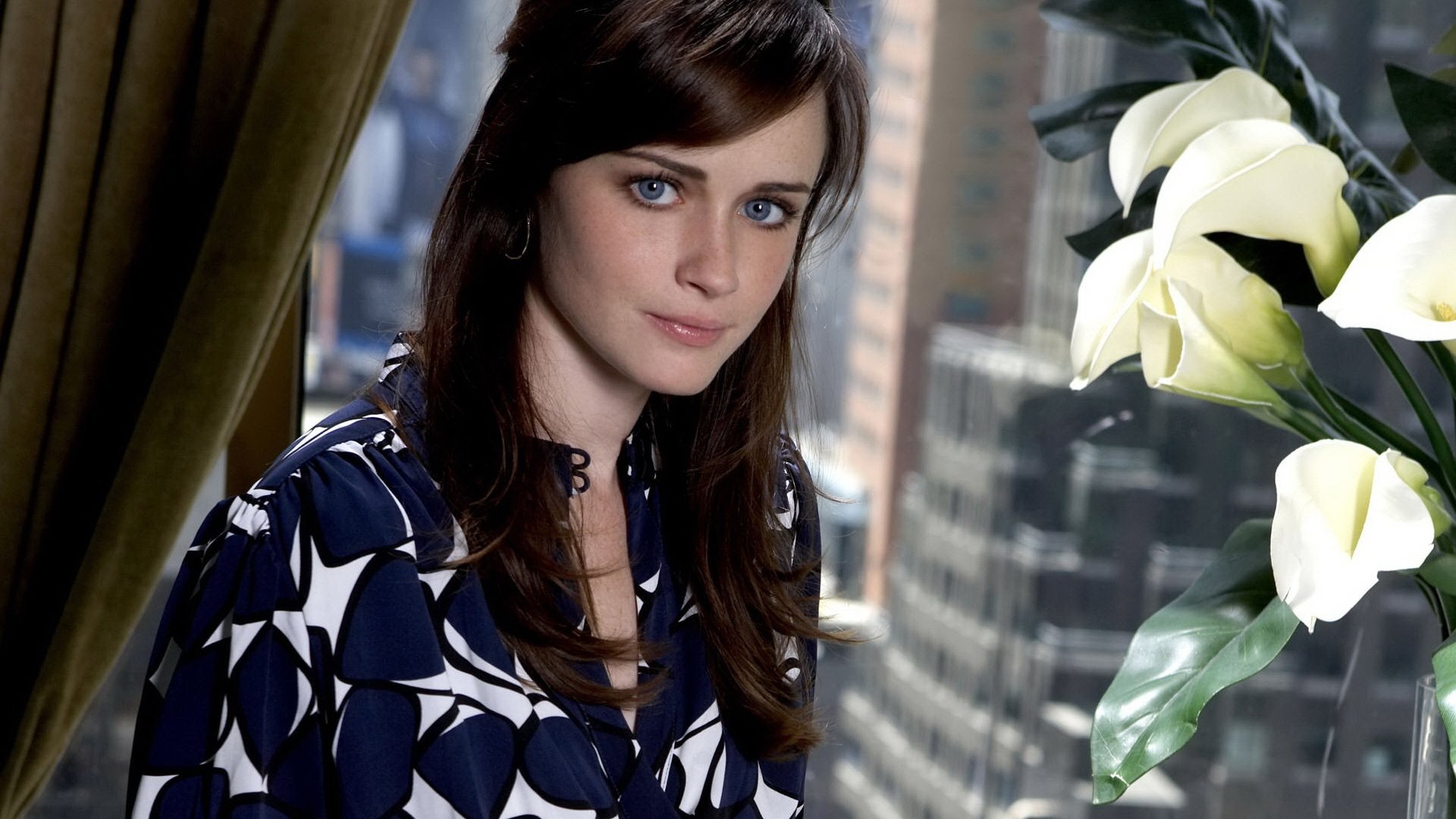 HD PC desktop wallpaper featuring celebrity Alexis Bledel posing indoors near a window with white flowers in the foreground.