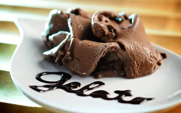HD PC desktop wallpaper featuring rich, creamy chocolate ice cream artfully served on a white plate with the word gelato written in chocolate syrup.