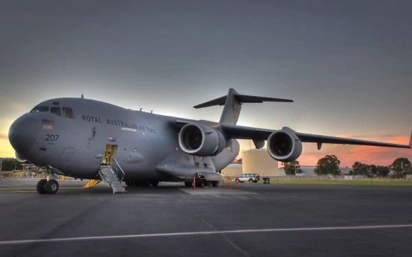 HD desktop wallpaper featuring a military Boeing C-17 Globemaster III aircraft parked on a runway at sunset.