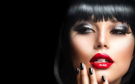 A stunning close-up of a woman's face featuring bold red lips, dramatic eye makeup, and sleek black hair, set against a dark background for an HD desktop wallpaper.