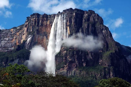 A breathtaking view of Angel Falls in Venezuela, showcasing a majestic waterfall cascading from a towering cliff surrounded by lush greenery and a clear blue sky.