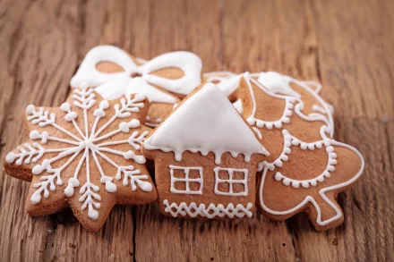 4K Ultra HD wallpaper featuring intricately decorated gingerbread cookies shaped like a snowflake, house, and angel on a wooden surface.