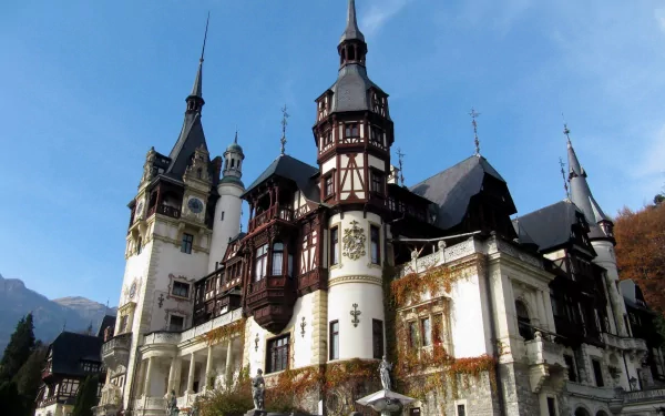 HD desktop wallpaper of Peles Castle, a man-made architectural landmark in Romania, showcasing intricate towers and detailed design against a clear blue sky.