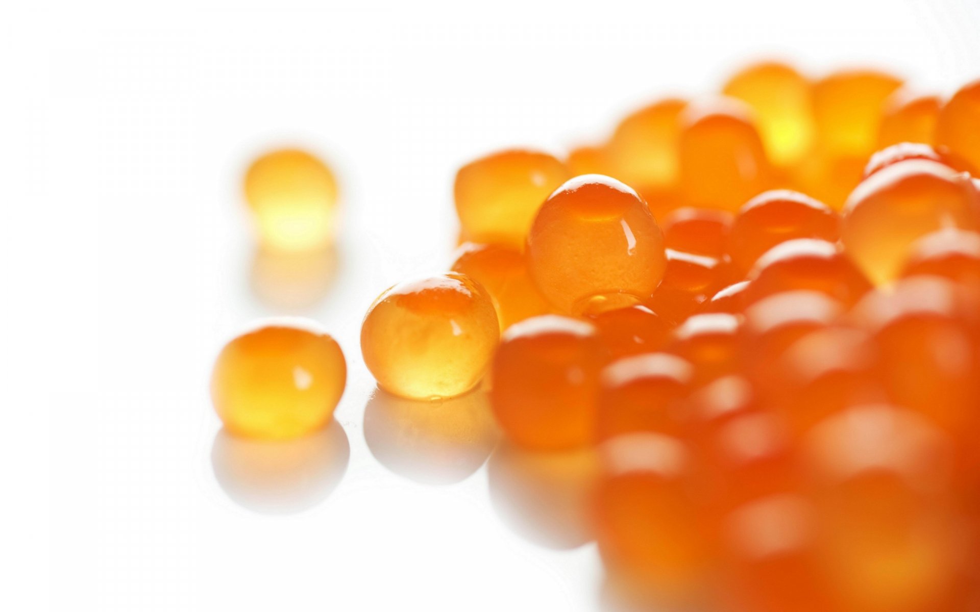 Close-up of vibrant orange caviar on a reflective white surface, designed as an HD PC desktop wallpaper and background.