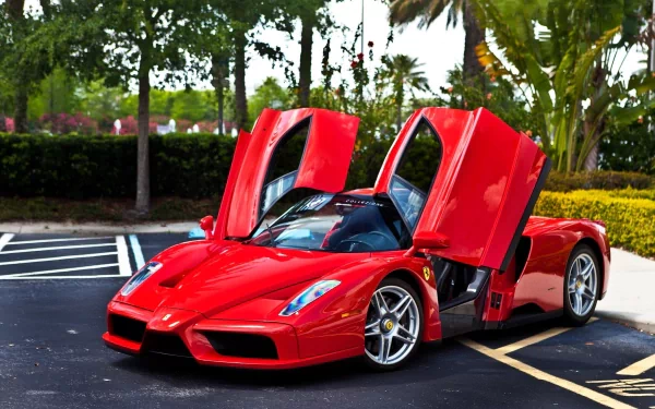 A striking Ferrari Enzo with its iconic doors open, showcased in a vibrant outdoor setting, serves as a captivating HD desktop wallpaper and background.