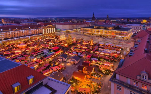 A vibrant nighttime view of a man-made Christmas market in Dresden, featuring illuminated stalls and historic buildings, captured as an HD PC desktop wallpaper background.