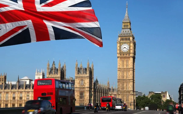 A vibrant view of Big Ben against a clear blue sky, with a Union Jack flag waving and red double-decker buses passing by, showcasing a lively scene of London in 4K Ultra HD.