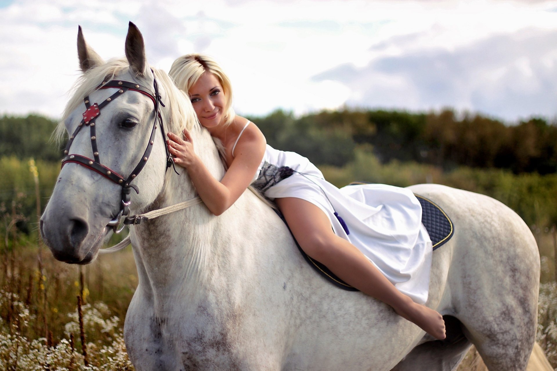 A serene horse stands in a grassy field with a woman in a white dress gently embracing it, creating a peaceful and harmonious scene in this HD PC desktop wallpaper.