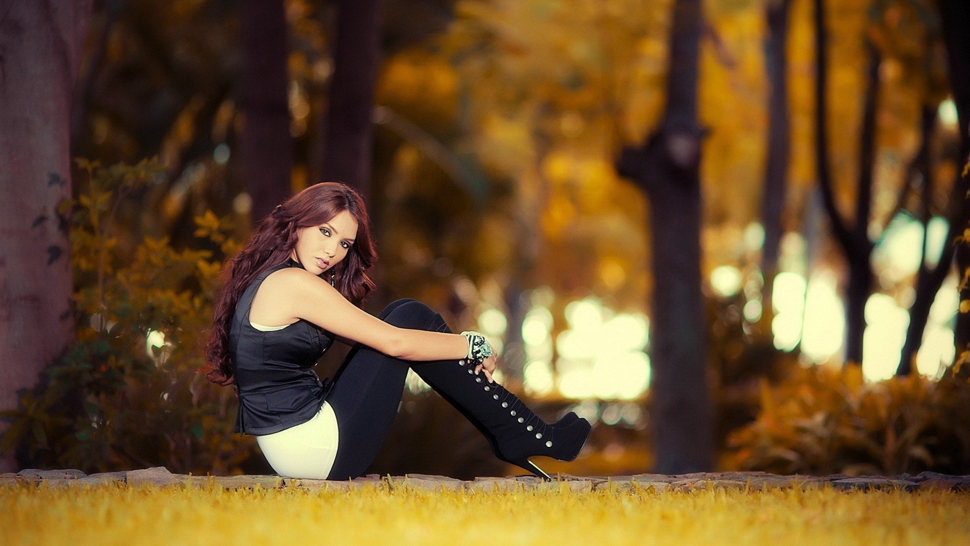 HD wallpaper of a model sitting outdoors in a wooded area, surrounded by autumn foliage.