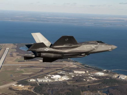 HD desktop wallpaper featuring a Lockheed Martin F-35 Lightning II military jet flying over a coastal landscape.