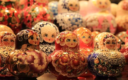 HD PC desktop wallpaper/background of man-made Russian nesting dolls (matryoshka) in colorful floral patterns, clustered on a warm, bokeh-lit surface.