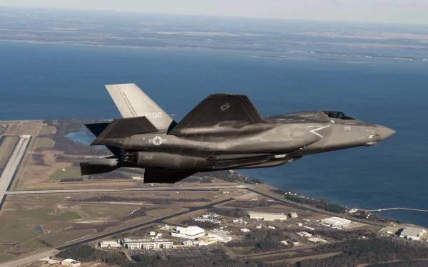 HD desktop wallpaper featuring a Lockheed Martin F-35 Lightning II military jet flying over a coastal landscape.