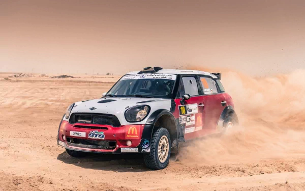 Rally-ready Mini Cooper vehicle kicking up dust across a desert landscape — HD PC desktop wallpaper background.