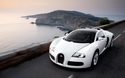 HD desktop wallpaper featuring a white Bugatti Veyron driving along a coastal road with a scenic mountain backdrop.