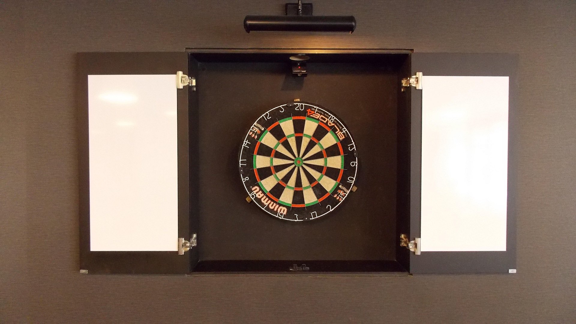 HD photo of a man-made dartboard with open cabinet doors, showcasing a classic dart board setup against a dark background.