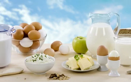 HD desktop wallpaper featuring a variety of fresh dairy products and eggs on a light wooden table against a blue sky background.