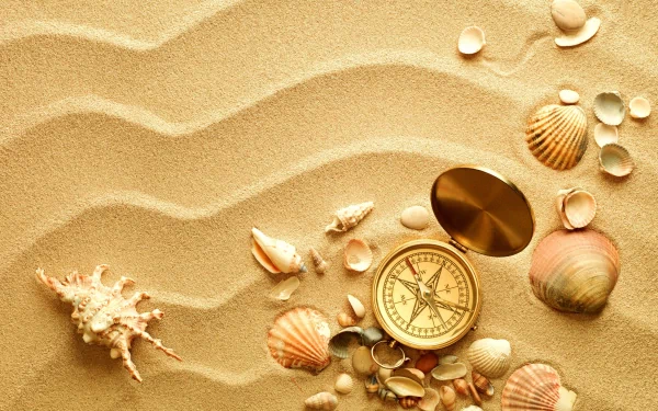 A still life 4K Ultra HD wallpaper featuring a man-made compass and various seashells arranged on rippled sand.