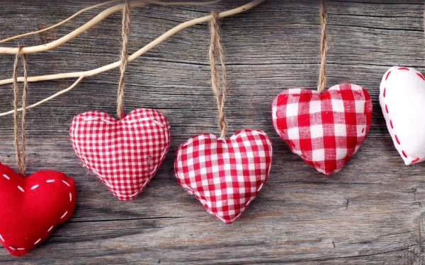 HD desktop wallpaper featuring red and white fabric hearts hanging on twine against a rustic wooden background, celebrating Valentine's Day holiday.
