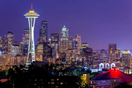 Nighttime view of the Seattle skyline featuring the illuminated Space Needle against a deep purple sky, captured in HD for a striking desktop wallpaper.