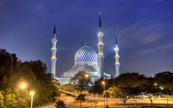 HD desktop wallpaper featuring the illuminated Sultan Salahuddin Abdul Aziz Mosque at dusk, showcasing its iconic blue dome and tall minarets against a twilight sky.