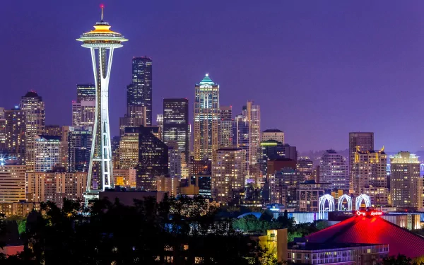 Nighttime view of the Seattle skyline featuring the illuminated Space Needle against a deep purple sky, captured in HD for a striking desktop wallpaper.