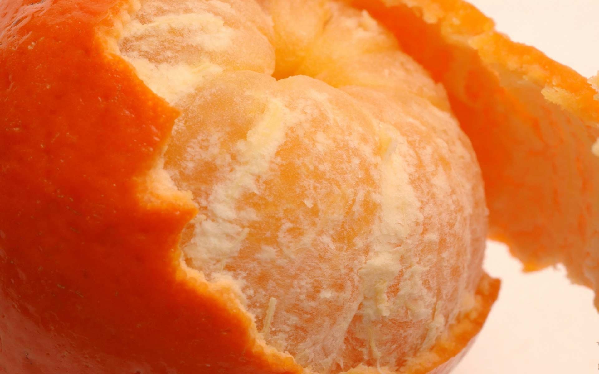 Close-up of a partially peeled mandarin orange, showcasing its vibrant segments in a high-definition PC desktop wallpaper background.