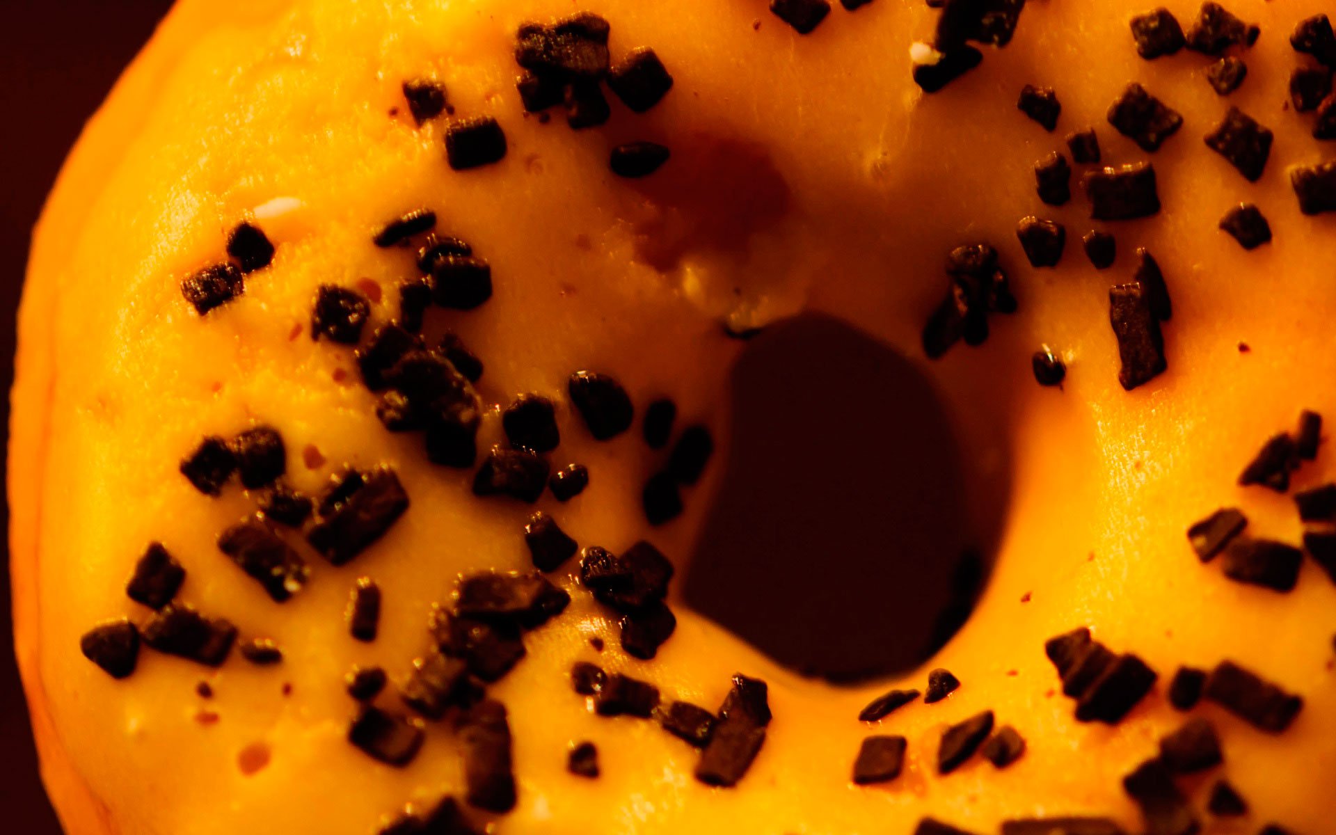 HD PC desktop wallpaper featuring a close-up of a doughnut with orange icing and chocolate sprinkles.