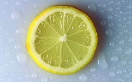 HD desktop wallpaper showing a close-up of a fresh lemon slice with water droplets on a smooth surface.