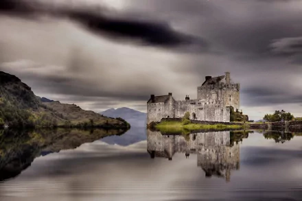 Eilean Donan Castle in Scotland stands reflected on calm waters under a dramatic cloudy sky, featured as an HD PC desktop wallpaper background.