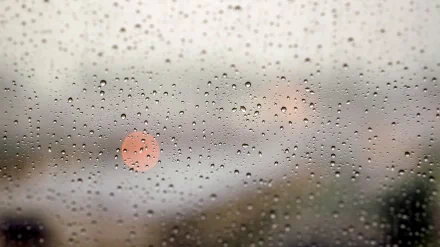A 4K Ultra HD photography wallpaper featuring raindrops on a window, softly blurring the city lights beyond.