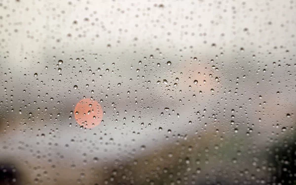 A 4K Ultra HD photography wallpaper featuring raindrops on a window, softly blurring the city lights beyond.