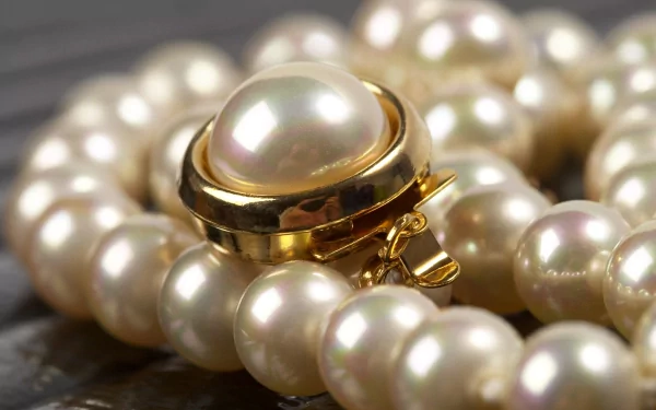 Close-up HD desktop wallpaper of man-made pearl jewelry with a gold clasp, showcasing the lustrous pearls in sharp detail.