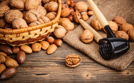 A wooden table is adorned with a basket of assorted nuts and a nutcracker, creating a warm and inviting food-themed HD desktop wallpaper.