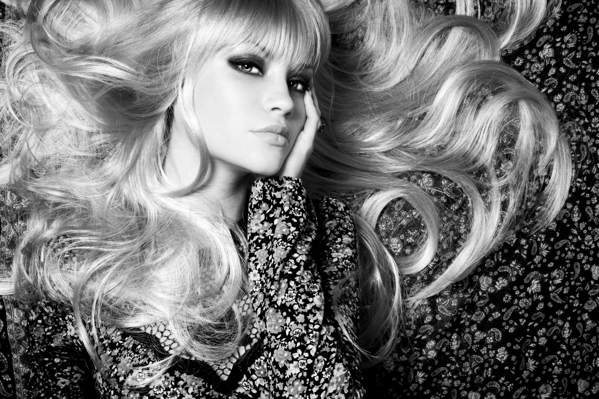 Black and white 4K Ultra HD wallpaper of a woman with long, flowing hair lying down, wearing a patterned floral outfit, captured in a high-resolution, detailed portrait.