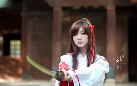 A woman in cosplay attire, holding a sword with a focused expression, stands against an architectural backdrop. The image is a vibrant HD desktop wallpaper and background.