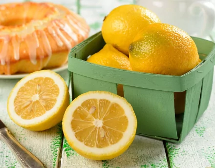 HD PC desktop wallpaper featuring fresh whole and halved lemons in a green basket alongside a glazed lemon bundt cake, highlighting vibrant food and lemon themes.