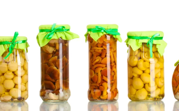 4K Ultra HD desktop wallpaper featuring jars of preserved mushrooms with green fabric covers, showcasing vibrant food textures against a clean white background.