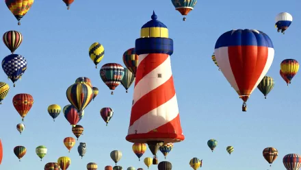 A vibrant scene of colorful hot air balloons fills the sky, with a striking lighthouse at the center, creating a captivating HD desktop wallpaper and background.