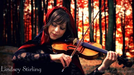 Lindsey Stirling plays the violin in a mystical forest setting, surrounded by vibrant autumn colors, creating an enchanting backdrop for this HD desktop wallpaper.