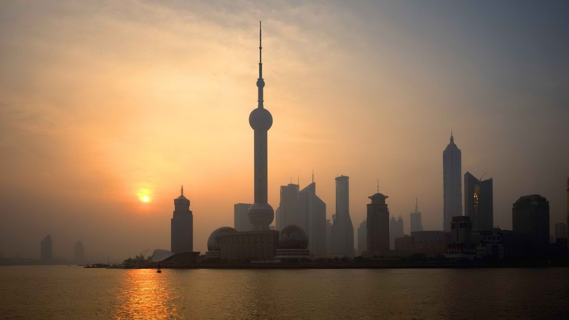 HD PC desktop wallpaper background: Shanghai man-made skyline at sunset, Oriental Pearl Tower and silhouetted skyscrapers reflected on the river.