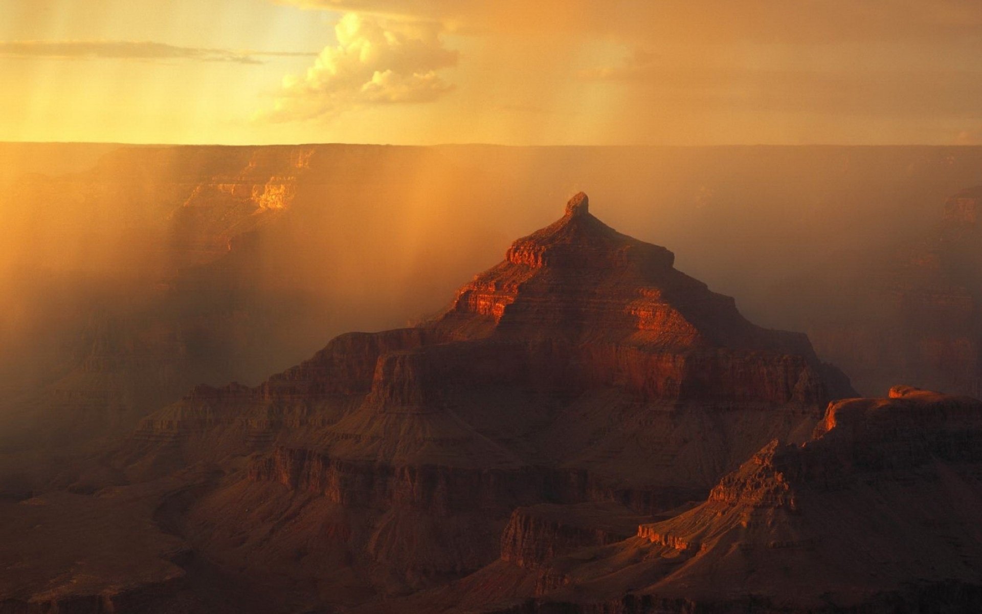 HD desktop wallpaper showcasing the Grand Canyon at sunset with warm light illuminating the rugged cliffs in this iconic national park landscape.