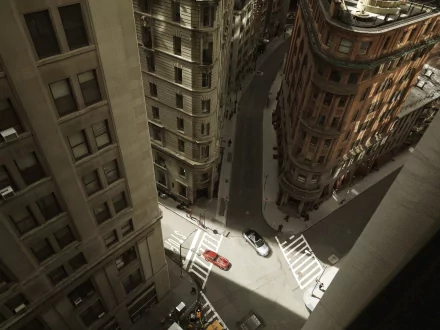 A Jaguar E-Type driving through narrow city streets, captured from above in an HD PC desktop wallpaper and background.