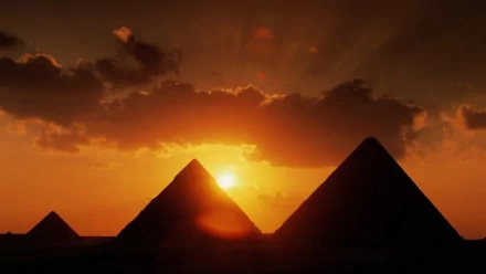HD PC desktop wallpaper/background: man-made pyramids silhouetted against a fiery sunset, sun breaking through clouds and casting an orange glow across the sky.