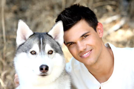 Taylor Lautner smiles warmly next to a Siberian Husky, set against a natural background, creating an inviting HD desktop wallpaper and background.