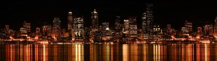 Seattle city skyline at night with illuminated buildings reflecting on the water, captured in a high-definition man-made scene for PC desktop wallpaper.