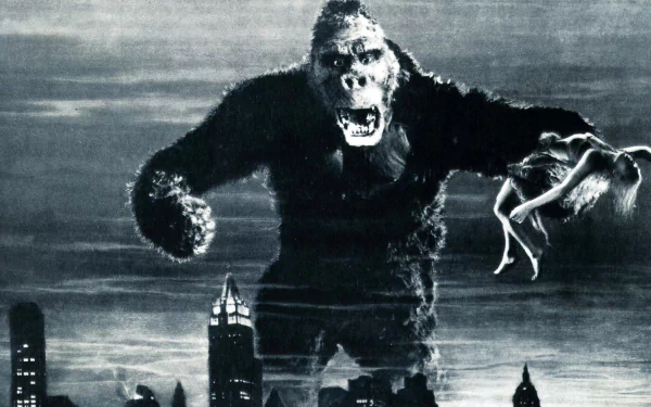 A dramatic black-and-white image of King Kong from the 1933 movie, towering over a city skyline while holding a woman, captures the iconic moment in cinematic history. HD desktop wallpaper background.